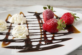 Strawberries and whipped cream with decorations over a square plate