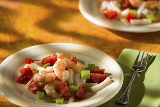 Shrimp salad with squid tomatoes and celery over an orange background