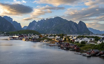 Village view of the fishing village Reine, Traditional red Rorbuer cabins, at sunset, rocky