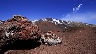 Large red lava boulder, red lava earth, snow on summit, Crateri Silvestri, Etna, volcano, Eastern