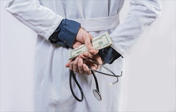 Dishonest doctor hiding money. Medical corruption and bribery concept, Corrupt doctor hiding money