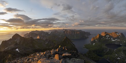 View over mountain peaks and sea, dramatic sunset, mountaineers at Hermannsdalstinden, with lakes