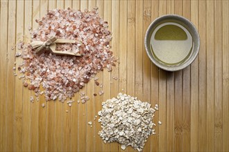 A flatlay studio photo of a pile of himalayan sea salt with a scoop, a pile of dried oatmeat, and a