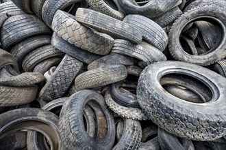 Old broken car tyres piled up up to form a mountain as a background