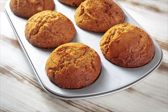 Orange muffins in a muffin tin on a rustic wooden kitchen table, easy baking, Food photography