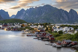 Village view of the fishing village Reine, Traditional red Rorbuer cabins, at sunset, rocky