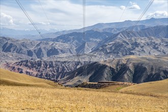 Electric pylon, eroded mountainous landscape with brown hills, mountains and steppe, Chuy province,