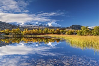 Reflection of the autumn landscape in Rondane National Park, snow-capped mountains, Doraldalen,