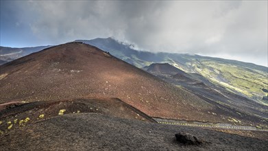 Red lava hill, cloudy sky, black crater, green mountain slopes, Crateri Silvestri, Etna, volcano,