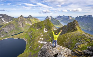 Mountaineer stretching his arms in the air, at the summit of Munken, mountain landscape with steep