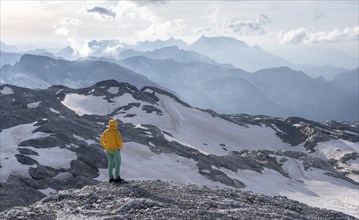 High alpine landscape, snowfields and rock, hiker Looking down into the valley from the Hochkönig,