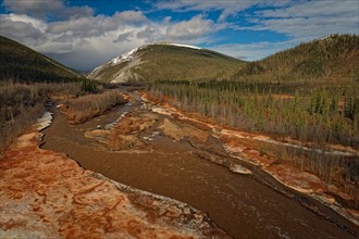 Drone image, view of Engineer Creek, ice break-up, intense red colouring of the water and ice,