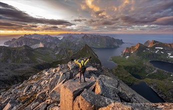 View over mountain top and sea, dramatic sunset, mountaineers at Hermannsdalstinden peak, with