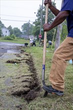 Detroit, Michigan, Volunteers clear weeds and grass in preparation for planting a roadside garden