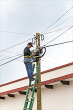 Electrician on ladder working on electricity power lines, Bacalar, Quintana Roo, Yucatan Peninsula,