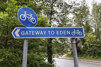 Blue traffic sign in the rain, cycle path, original signpost with inscription, Gateway to Paradise,