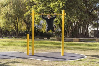 Attractive athlete doing exercises on a crossbar in a public car