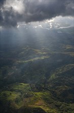 Aerial of sun breaking through the clouds over the volcanic landscape, Viti Levu, Fiji, South