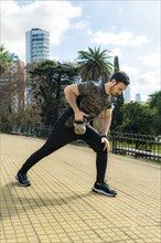 Young latin man doing exercises with kettlebell outdoor. Weightlifting workout. Sports, fitness