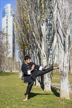 An athletic martial arts fighter practicing kicks in a public park.