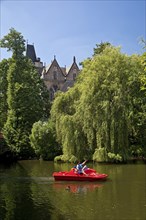 Father and son in a pedal boat on the river Lahn with the Old University in the background,