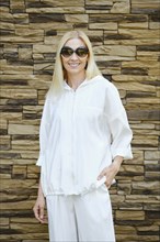 Medium closeup portrait of happy smiling fashionable woman wearing trendy white hoodie and trousers