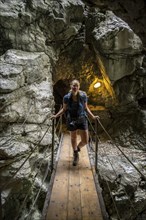 Hiker in a tunnel, Hammersbach flows through Höllentalklamm, near Garmisch-Partenkirchen,