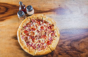 Top view of ham and cheese pizza on wooden table. Ham pizza with cheese edge on wooden background