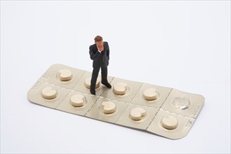 Symbol photo, man (figure) standing helplessly on a blister with tablets, side effect