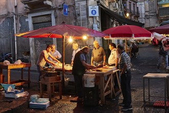 Early morning, fish market, illuminated stall, vendor, old town, Catania, east coast, Sicily,