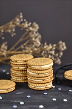 Stack of cream filled sandwich double cookies on dark background