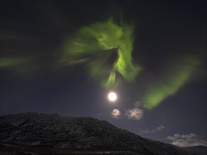 Northern lights explosion and brightly shining moon