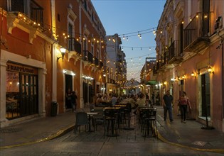 Restaurant tables in street at night with hanging lights, Campeche city, Campeche State, Mexico,