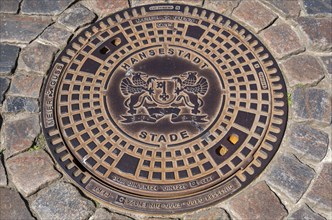 Manhole cover, manhole cover with city coat of arms and cobblestones, Hanseatic City of Stade,