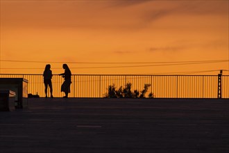 Two woman on the terrace of the Dresden Congress Centre in front of the summer evening sky