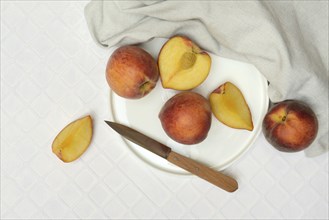 Cut peaches with knife on plate (Prunus persica)