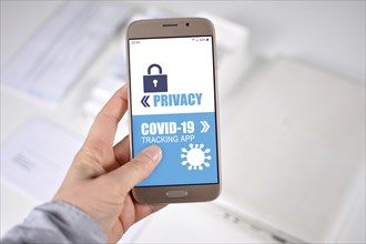 Corona Virus Tracking App privacy concerns concept with hand holding cell phone with application