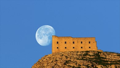 Morning light, super clear blue sky, huge full moon, fortress-like building on the mountain,