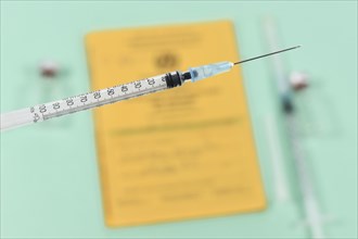 Vaccine concept with close up of syringe in front of blurry yellow international certificate of