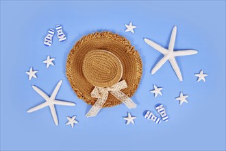 White starfish, summer straw hat and sandals on blue background