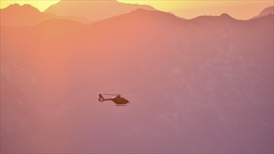 Rescue helicopter Christoph in flight in the evening over the Berchtesgaden Alps, Bavaria, Germany,