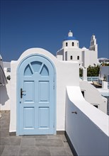 Terrace with blue door and church of Panagia Platsani, Ia, Oia, Santorini, Greece, Europe