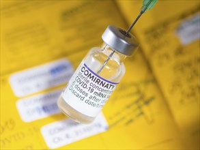 Symbolic image Corona vaccine Comirnaty in front of a vaccination certificate