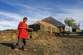 Native boy selling something in front of his house, vulcano in background. Fogo. Cabo Verde. Africa