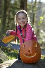 Girl playing with a Halloween pumpkin, in nature, child in autumn, Upper Bavaria, Bavaria, Germany,