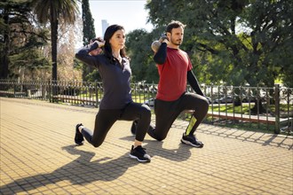 Man and woman lifting Kettlebells Together. Outdoor sports concept