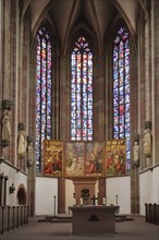 Interior view of the chancel with stained glass windows and folding altar with painting of the