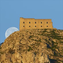 Morning light, super clear blue sky, huge full moon, sets behind mountain, fortress-like building