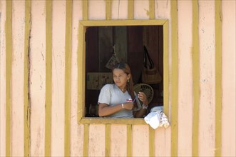 Young woman of a caboclos tribe combing her hair at the window of her house along the Amazon River,