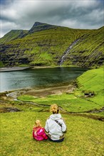 Woman with her child looking at the beautiful fjord of Saksun, Streymoy, Faroe islands, Denmark,